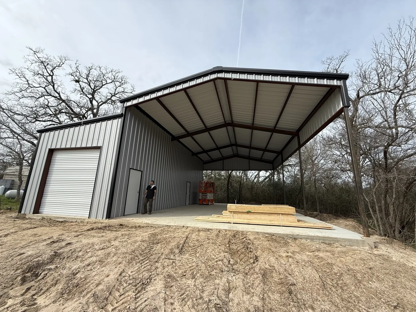 Metal building and covered work area completed on a wooded property