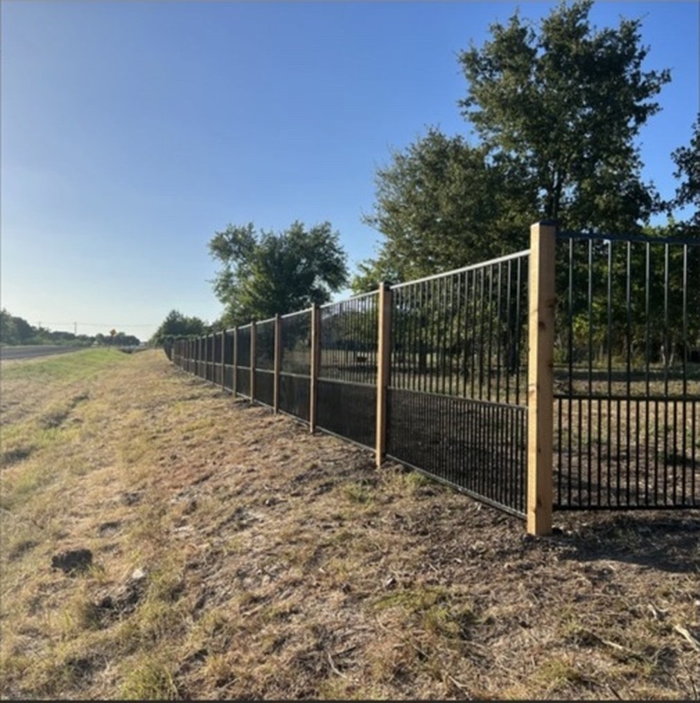 White Hog ranch perimeter fence with black metal rails and cedar posts